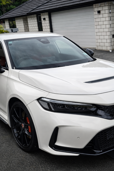 White car with black rims parked in front of a garage.