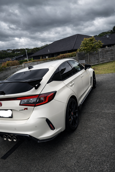 White Honda Civic Type R parked on a road with a cloudy sky.